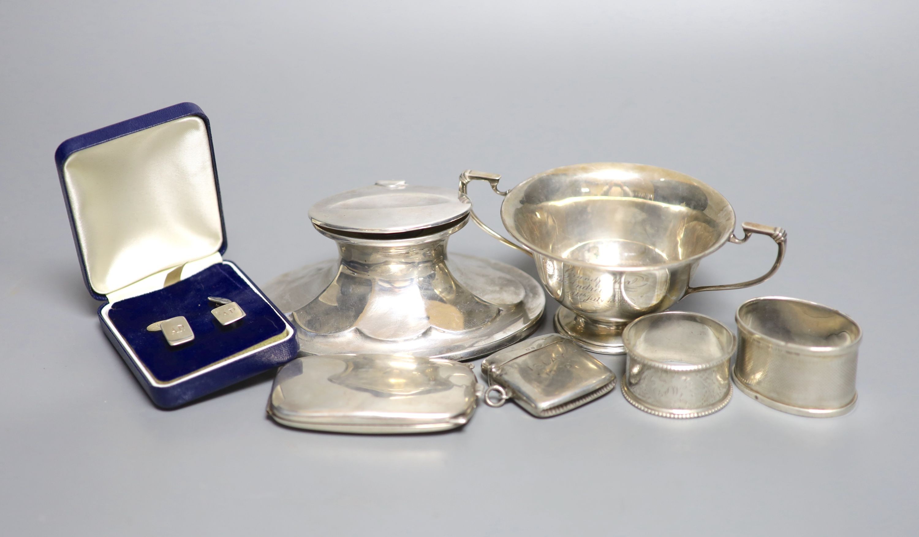 A Scottish silver mounted oval inkwell, 13.2cm, a small silver bowl, silver vesta case, silver cigarette case, two silver napkin rings and two other items.